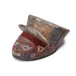 A Yoruba gelede mask Nigeria wearing a peaked hat and with pigment, 32cm long.