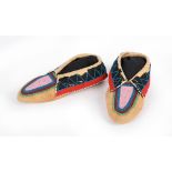 A pair of Delaware moccasins Plains buckskin, cloth and coloured glass beads, circa 1880, 23.5cm