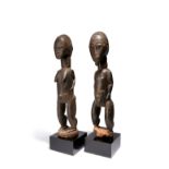 A Baule couple Ivory Coast male and female standing figures with linear coiffure, her with a short