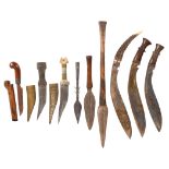A small collection of edged weapons, comprising: two kukris with wooden hilts, another with staghorn