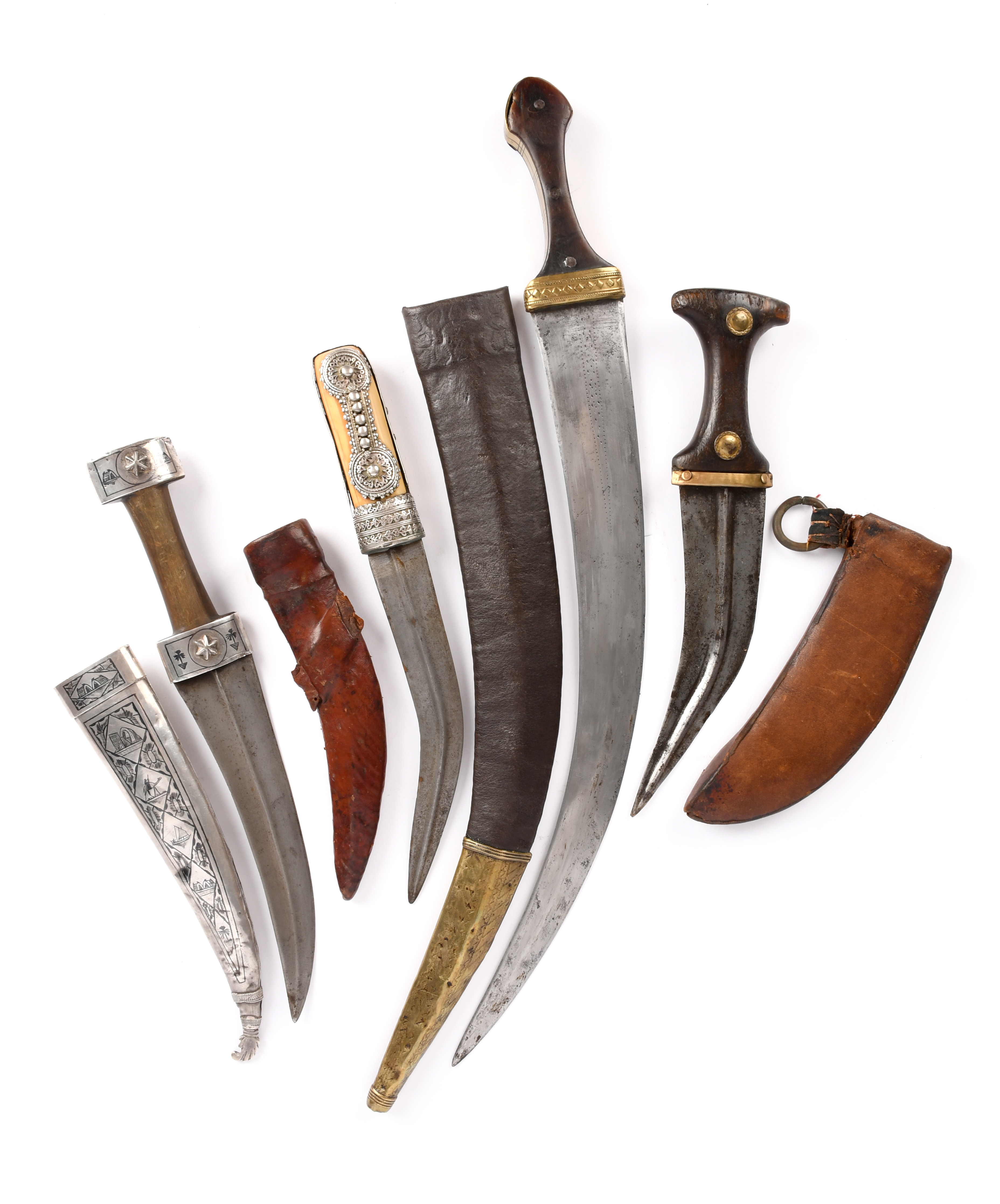 Four Middle Eastern daggers (jambiya): i) an Iraqi example with 8.25 in. blade, silver hilt and