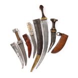 Four Middle Eastern daggers (jambiya): i) an Iraqi example with 8.25 in. blade, silver hilt and