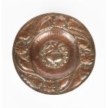 A repousse copper charger probably by John Pearson, hammered to the well with a grotesque bird