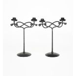 A pair of patinated wrought iron twin-branch candlesticks designed by Edward Spencer, probably