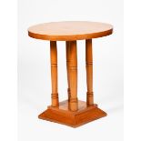A beech laminate side table, circular top on four turned, cylindrical columns and flaring square