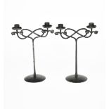 A pair of patinated wrought iron twin-branch candlesticks designed by Edward Spencer, probably