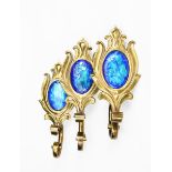 Three enamelled brass curtain ties, each cast as a stylised flower stem, set with vivid blue