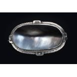A George Hunt silver and abalone brooch, oval frame with hammered texture, strap and rivet panels