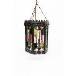 A patinated metal hall lantern, hexagonal section with pierced arch mantel border, set with coloured