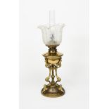 An Art Nouveau brass oil lamp, tripod body on domed base, with flume and frosted glass shade with