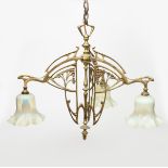 An Art Nouveau brass three light ceiling light, cast and pierced with stylised whiplash berried
