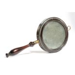 A LATE REGENCY MAHOGANY HAND MIRROR C.1820 the circular plate within a moulded frame, with a brass