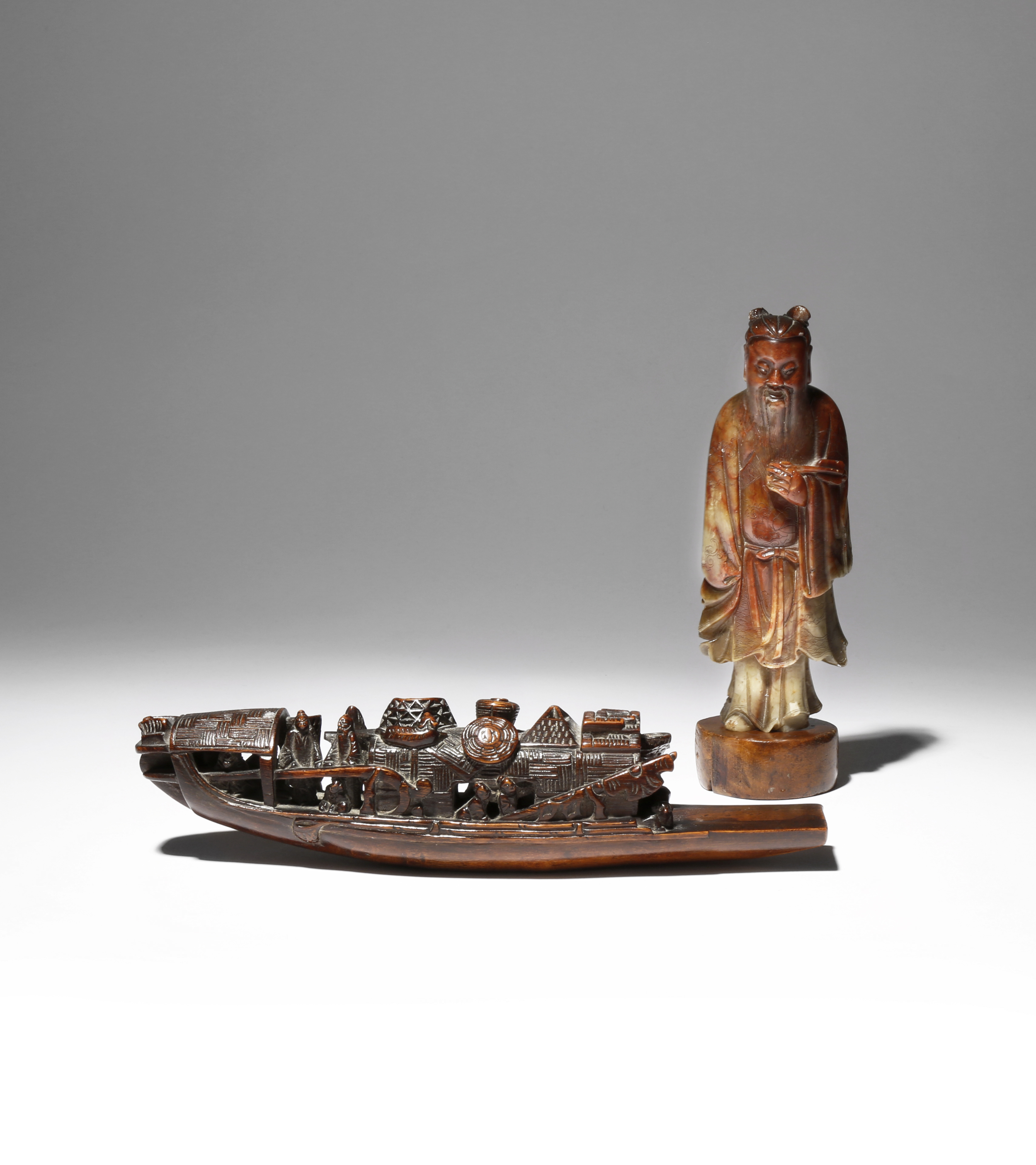 A CHINESE SOAPSTONE FIGURE AND A BAMBOO CARVING OF A SAMPAN 19TH/EARLY 20TH CENTURY The figure