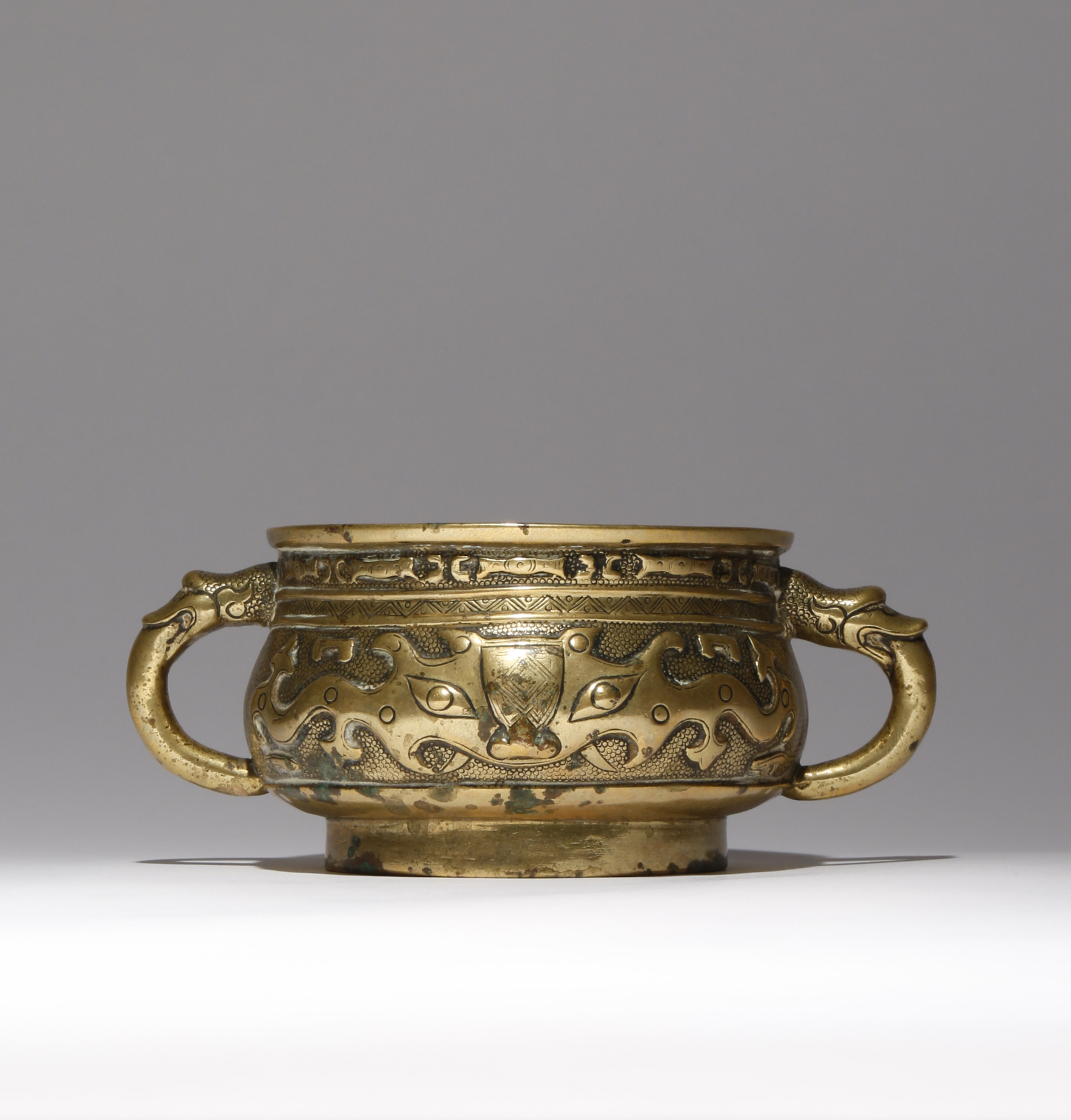 A CHINESE BRONZE INCENSE BURNER QING DYNASTY The bombé-shaped body cast in relief with archaistic