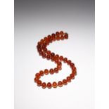 AN AMBER BEAD NECKLACE 20TH CENTURY With compressed circular beads, the gilt-metal clasp set with