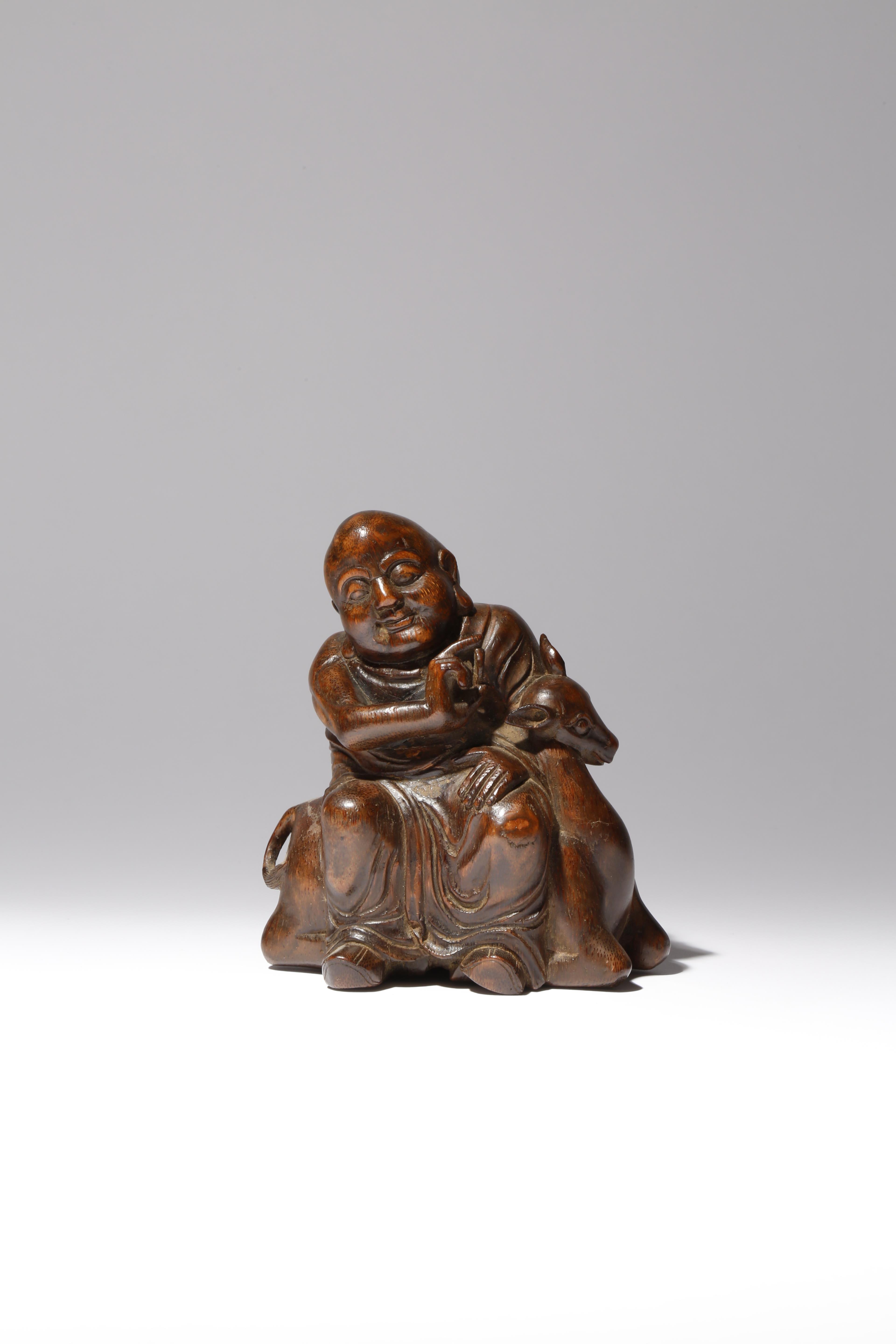 A CHINESE BAMBOO FIGURE OF A LUOHAN AND A DEER QING DYNASTY The figure carved seated upon a