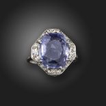 An Edwardian colour-change sapphire and diamond cluster ring, the cushion-shaped sapphire weighs