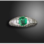 An Art Deco emerald and diamond ring by Tiffany & Co, the emerald-cut emerald is flanked by