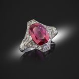 An early 20th century ruby and diamond-set platinum ring, the oval-shaped ruby weighs