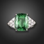 A tourmaline and diamond dress ring, the cushion-shaped green tourmaline is flanked with