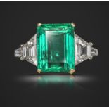 An emerald and diamond ring, the emerald-cut emerald weighs 5.03cts, set with a trapeze-shaped and