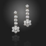 A pair of diamond drop earrings, the flowerhead section suspending from an articulated drop, set