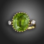 A peridot and diamond three-stone ring, the cushion-shaped peridot is claw set, with a round