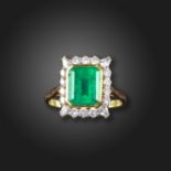 An emerald and diamond cluster ring, the emerald-cut emerald weighs approximately 4.50cts, set