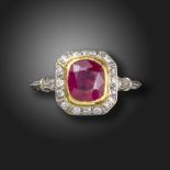 A ruby and diamond cluster ring, set with a cushion-shaped ruby within a surround of old circular-