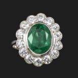 An emerald and diamond cluster ring, centred with an oval-shaped emerald within a surround of