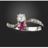 A ruby and diamond crossover ring, set with a circular-cut ruby and an old cushion-shaped diamond,