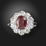 A ruby and diamond cluster ring, the oval-shaped ruby weighs 3.09cts, set within a surround of round