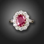 A ruby and diamond cluster ring, the oval-shaped ruby set within a surround of old circular-cut