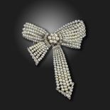 An Edwardian seed pearl and diamond-set bow brooch, centred with an old circular-cut diamond, the