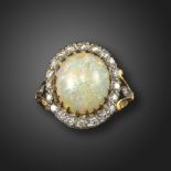 An opal and diamond cluster ring, the solid white opal cabochon is set within a surround of single-