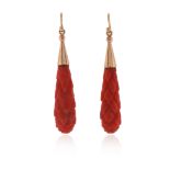 A pair of coral drop earrings, the elongated carved coral drops suspend from gold caps, shepherd's
