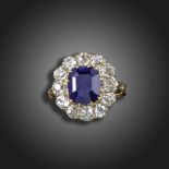 A sapphire and diamond cluster ring, the cushion-shaped sapphire is set within a surround of old