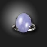 A lavender jade and diamond ring, the jadeite cabochon is set with diamond shoulders in white