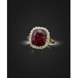 A spinel and diamond cluster ring, the cushion-shaped red spinel weighs 5.60cts, set within a