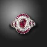 A ruby and diamond cluster ring, centred with an oval-shaped ruby within a surround of round