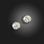 A pair of diamond stud earrings, the round brilliant-cut diamonds are rubover-set in white gold,