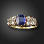 A sapphire and diamond half-hoop ring, centred with an old cushion-shaped sapphire, with pairs of