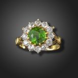 A demantoid garnet and diamond cluster ring, the circular-cut garnet set within a surround of old