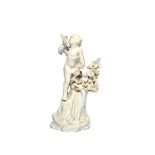 A Plymouth white-glazed figure of a putto c.1770, standing on top of a tall rocky base beside a