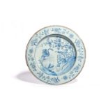 A Liverpool delftware charger c.1760, painted with two European travellers seated beneath