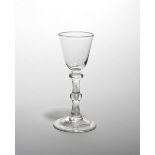 A wine glass c.1750, with a small rounded funnel bowl raised on a double-knopped stem above a folded