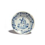 A Delft charger late 17th century, painted in blue with a windmill to the well, the wide rim with