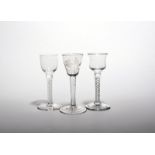 Three small wine glasses c.1760, one with a rounded funnel bowl engraved with a flower raised on a