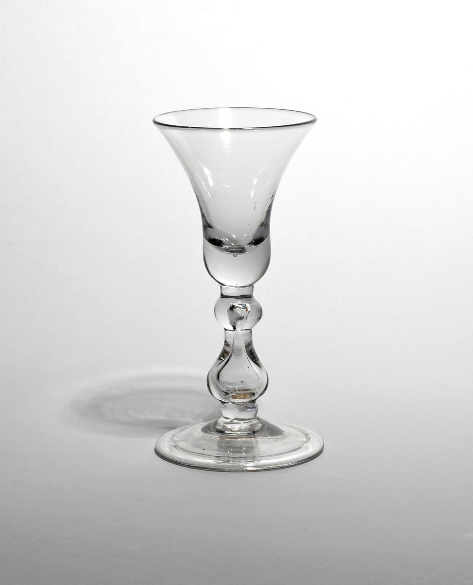 A heavy baluster glass c.1710, with a generous bell bowl raised on a baluster stem with cushion knop