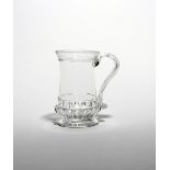 A glass tankard c.1780, the slightly waisted form with a band of gadrooning above the circular foot,